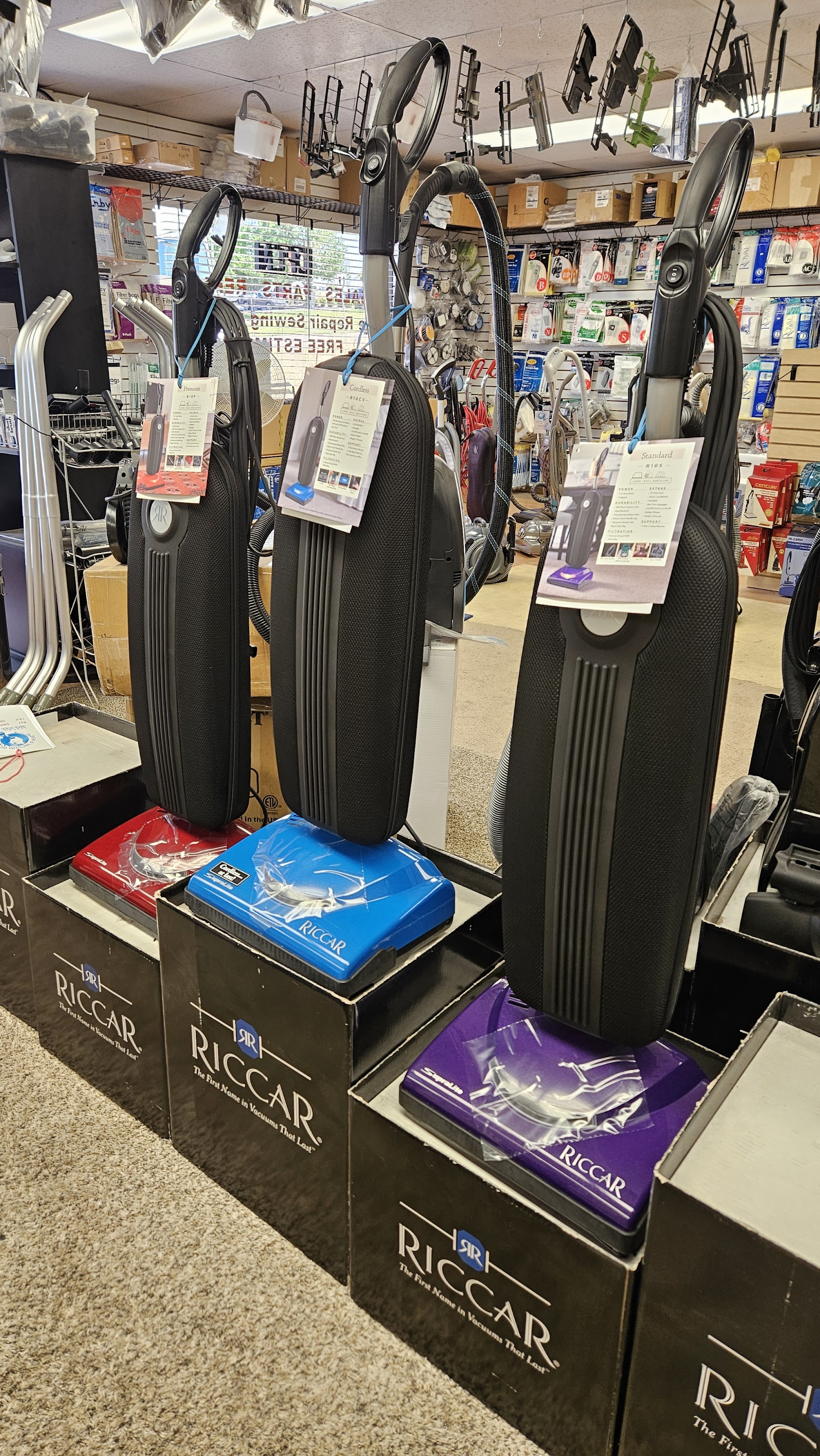 Riccar upright vacuums on display inside the shop, parts wall behind