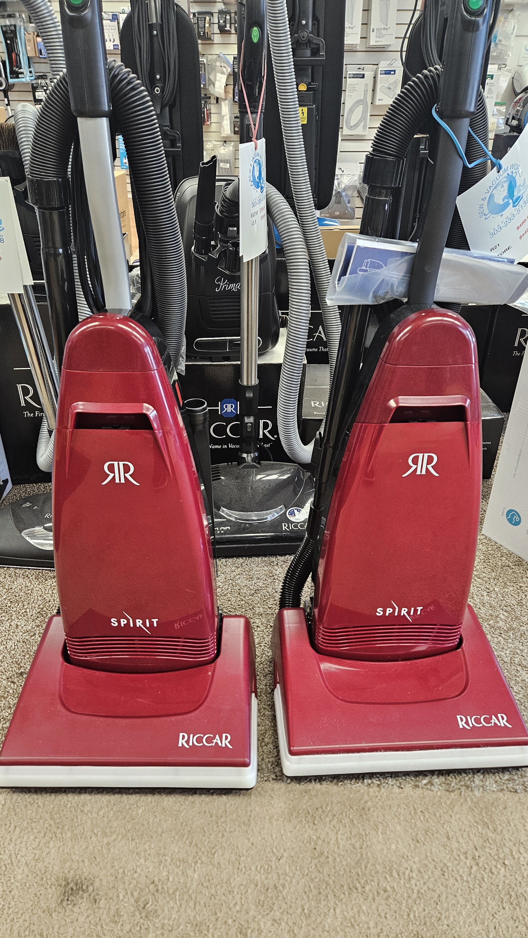Two red Riccar Spirit uprights ready for pickup inside Sew & Vacuum World