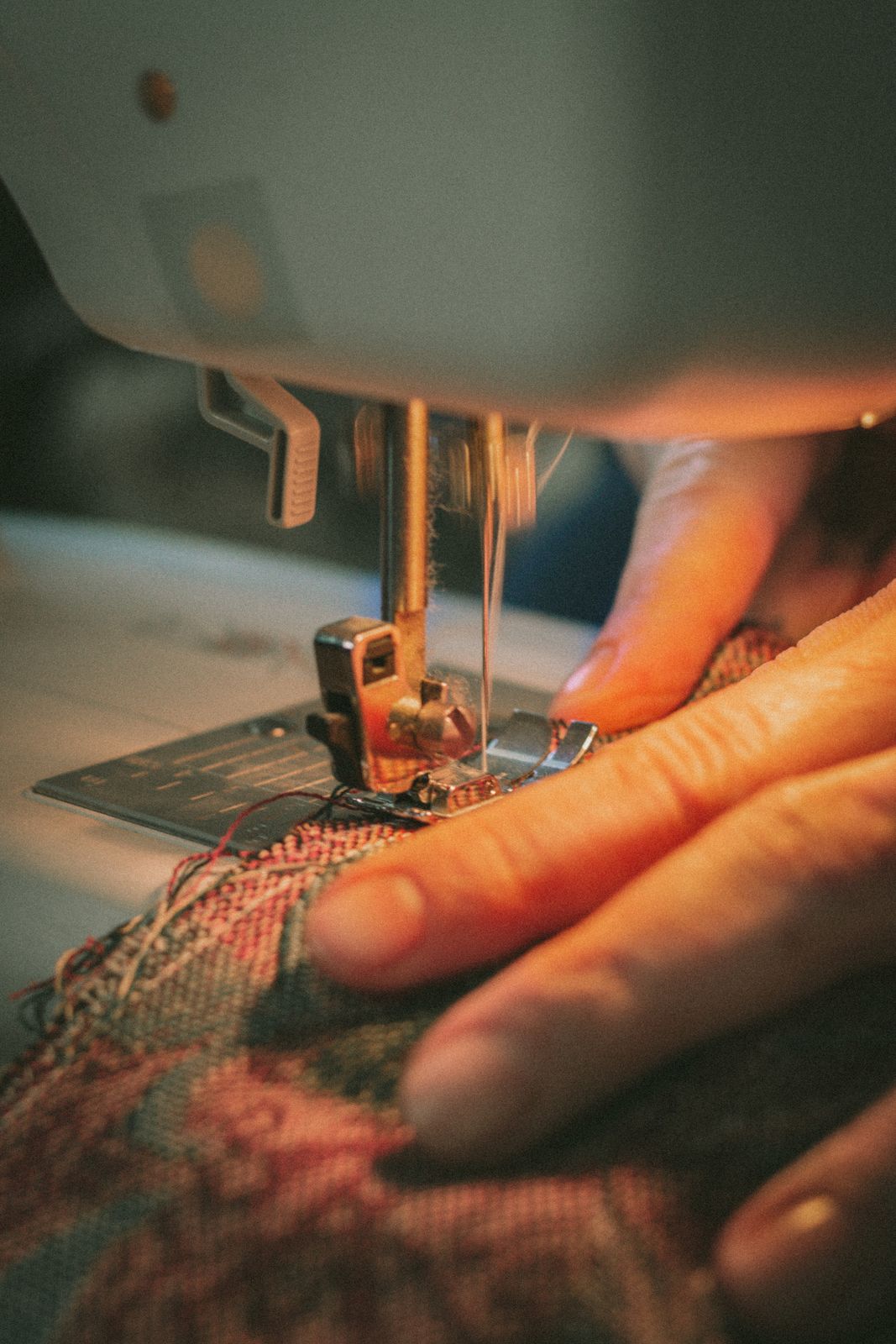 Hands guiding fabric under the needle of a sewing machine at the bench